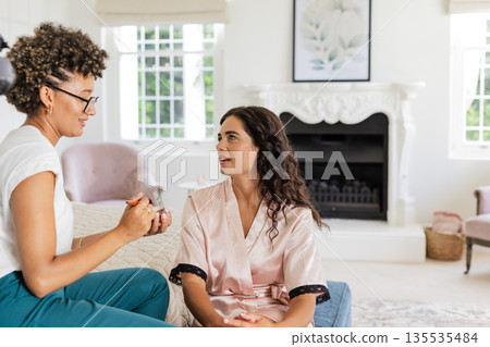 Bride in silk robe talking with makeup artist in elegant living room 135535484