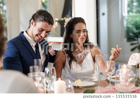 Bride and groom laughing together at wedding reception, enjoying joyful celebration 135535516