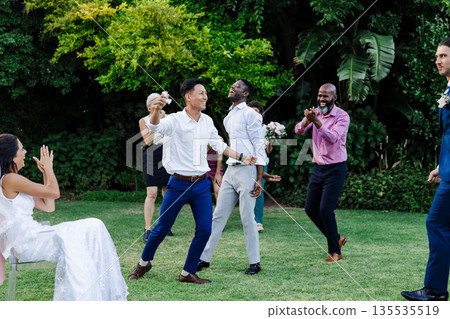 Guests joyfully dancing and celebrating together at outdoor wedding reception Guests joyfully dancing and celebrating together at outdoor wedding reception 135535519