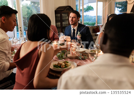 Guests enjoying dinner and conversation at elegant wedding reception table 135535524