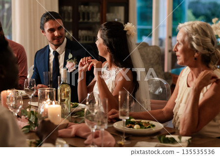 Bride and groom sharing joyful conversation with guests at elegant wedding dinner Bride and groom sharing joyful conversation with guests at elegant wedding dinner 135535536