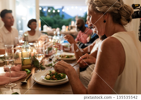 At wedding reception, guests sharing laughter and conversation during elegant dinner 135535542
