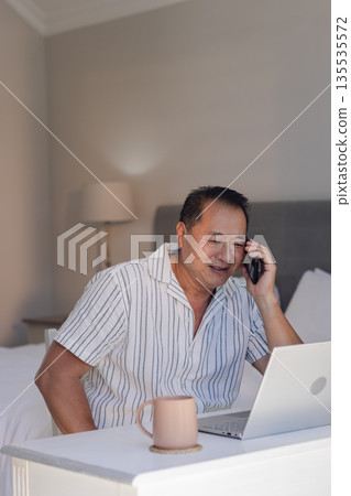Senior man using smartphone and laptop at home, enjoying conversation Senior man using smartphone and laptop at home, enjoying conversation 135535572