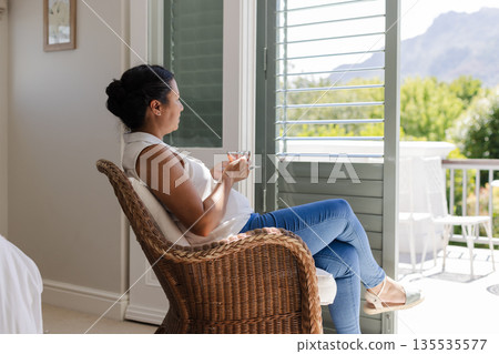 Relaxing at home, woman enjoying tea on balcony with mountain view 135535577