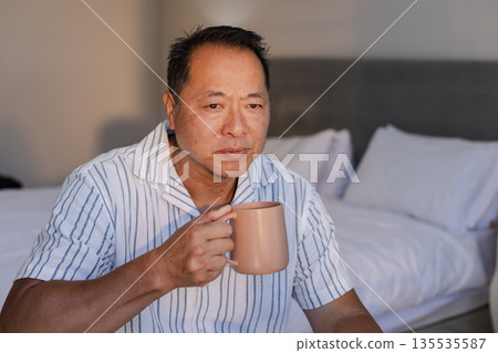 Relaxing at home, senior man enjoying morning coffee in cozy bedroom Relaxing at home, senior man enjoying morning coffee in cozy bedroom 135535587