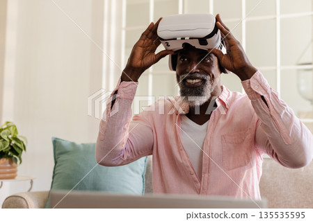 Using VR headset at home, African American man smiling during virtual experience 135535595