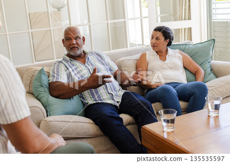 Senior couple discussing important matters while sitting on living room sofa Senior couple discussing important matters while sitting on living room sofa 135535597