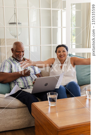 Senior couple celebrating good news at home, smiling and using laptop together Senior couple celebrating good news at home, smiling and using laptop together 135535599