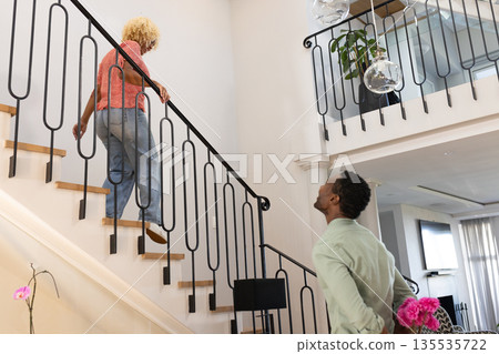 Friends enjoying conversation on staircase in modern home, sharing joyful moment Friends enjoying conversation on staircase in modern home, sharing joyful moment 135535722