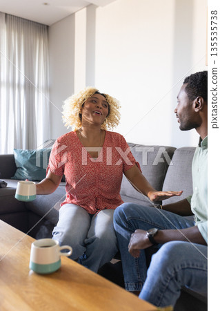 Friends enjoying coffee and conversation at home, sharing laughter and stories Friends enjoying coffee and conversation at home, sharing laughter and stories 135535738