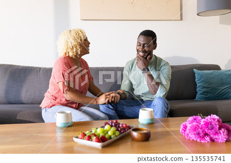 Friends enjoying conversation on sofa, sharing laughter over coffee and snacks 135535741