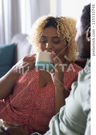 African American woman enjoying coffee with friend at home, smiling and relaxed African American woman enjoying coffee with friend at home, smiling and relaxed 135535748