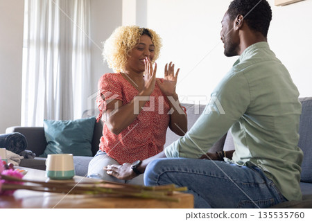 African American friends laughing and talking on sofa at home, enjoying conversation 135535760