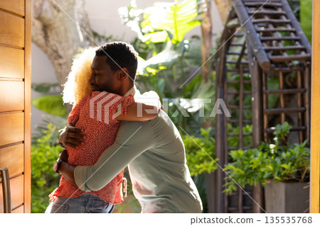 Friends embracing warmly in sunny garden, enjoying joyful outdoor reunion 135535768