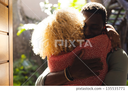 African American man hugging friend warmly outdoors, both smiling and embracing 135535771