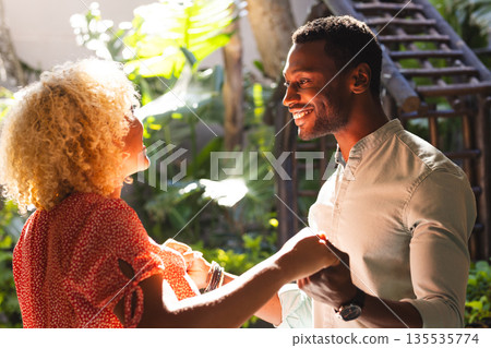 Friends enjoying conversation and laughter outdoors in sunny garden setting 135535774