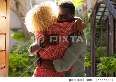Friends embracing warmly outdoors, enjoying heartfelt reunion in sunny garden 135535775