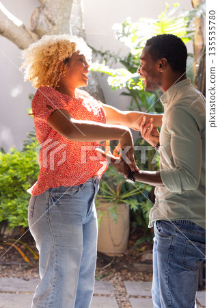 Dancing and laughing, friends spending time together in sunny outdoor setting 135535780