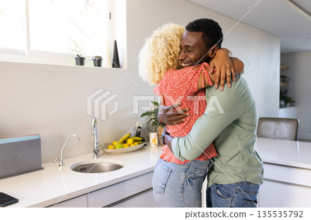 African American man and woman hugging in modern kitchen, expressing happiness African American man and woman hugging in modern kitchen, expressing happiness 135535792