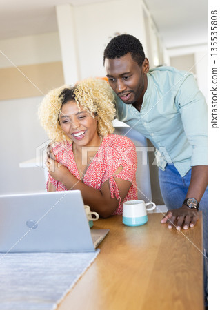Couple enjoying video call on laptop at home, smiling and drinking coffee 135535808
