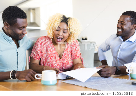 African American friends laughing and discussing documents at home over coffee 135535818
