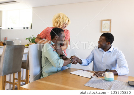 African American friends shaking hands at home, celebrating successful agreement 135535820