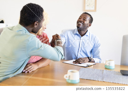 Smiling friends shaking hands at table, enjoying coffee and conversation together Smiling friends shaking hands at table, enjoying coffee and conversation together 135535822