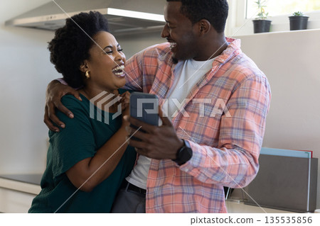 Holding smartphone and laughing, friends enjoying conversation together at home Holding smartphone and laughing, friends enjoying conversation together at home 135535856