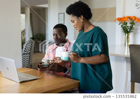 African American friends enjoying coffee and conversation at home with laptop 135535862