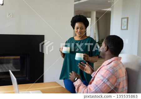 African American friends enjoying coffee together at home, smiling and chatting African American friends enjoying coffee together at home, smiling and chatting 135535863