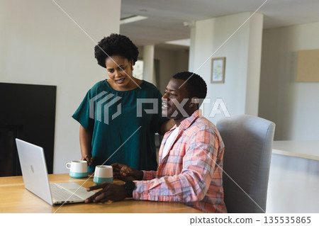 Discussing project, African American friends using laptop and drinking coffee at home Discussing project, African American friends using laptop and drinking coffee at home 135535865