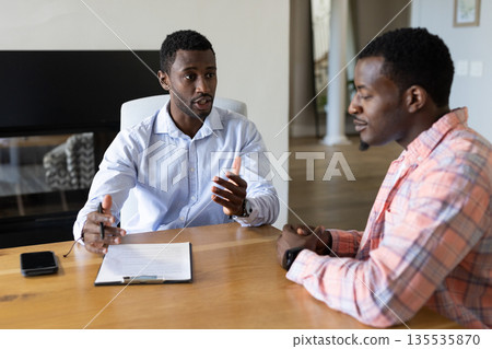 Two men discussing business strategy at table with documents and smartphone 135535870