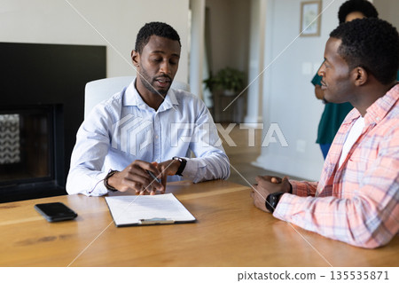 Discussing contract details, African American men focusing on agreement in home office Discussing contract details, African American men focusing on agreement in home office 135535871