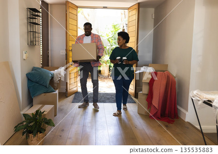 Couple unpacking boxes in new home, smiling and enjoying fresh start Couple unpacking boxes in new home, smiling and enjoying fresh start 135535883