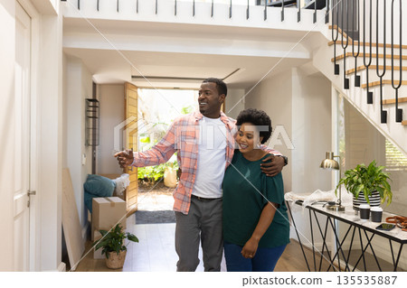 African American couple happily exploring new home, embracing and smiling together African American couple happily exploring new home, embracing and smiling together 135535887