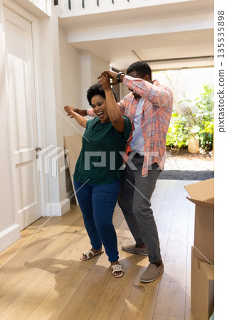 Happy couple dancing together in new home surrounded by moving boxes 135535898