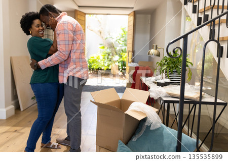African American couple embracing happily while unpacking boxes in new home African American couple embracing happily while unpacking boxes in new home 135535899