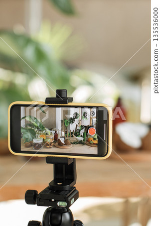 A smartphone mounted on a tripod is recording a table filled with fresh fruits, jars of ingredients, and plants, suggesting content creation for food blogging or vlogging A smartphone mounted on a tripod is recording a table filled with fresh fruits, jars of ingredients, and plants, suggesting content creation for food blogging or vlogging 135536000