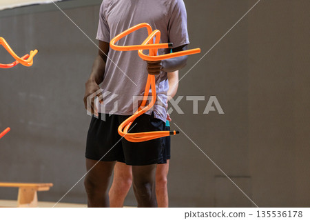 Diverse male training partners gripping bright agility poles standing in gymnasium Diverse male training partners gripping bright agility poles standing in gymnasium 135536178