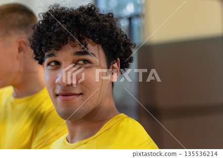 Male teammates standing in sports hall wearing matching yellow athletic shirts 135536214