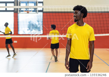 Diverse male partners in yellow shirts playing volleyball on court near net, copy space Diverse male partners in yellow shirts playing volleyball on court near net, copy space 135536246