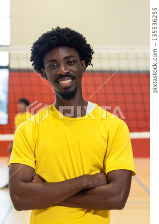 African american male partners in yellow jersey posing with arms crossed on gym court showing net African american male partners in yellow jersey posing with arms crossed on gym court showing net 135536255