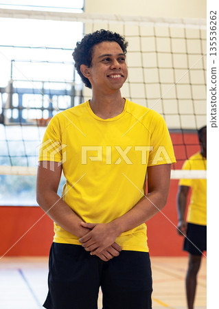 African american male teammates wearing yellow shirts standing on volleyball court next to net 135536262