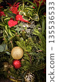 festive arrangement of glittering colorful Christmas ornament balls nestled in lush evergreen branches, creating a warm, celebratory mood perfect for holiday decor and seasonal stock photography 135536533