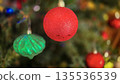 festive arrangement of glittering colorful Christmas ornament balls nestled in lush evergreen branches, creating a warm, celebratory mood perfect for holiday decor and seasonal stock photography 135536539