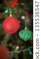 festive arrangement of glittering colorful Christmas ornament balls nestled in lush evergreen branches, creating a warm, celebratory mood perfect for holiday decor and seasonal stock photography 135536547