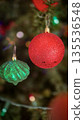 festive arrangement of glittering colorful Christmas ornament balls nestled in lush evergreen branches, creating a warm, celebratory mood perfect for holiday decor and seasonal stock photography 135536548