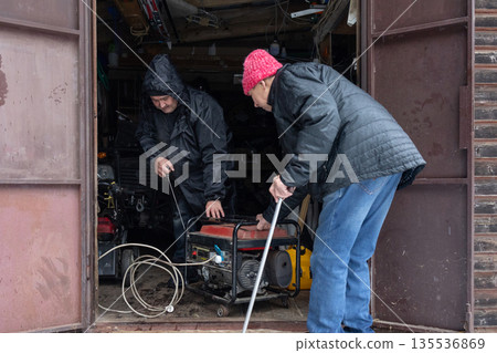 Two men starting generator in winter garage 135536869