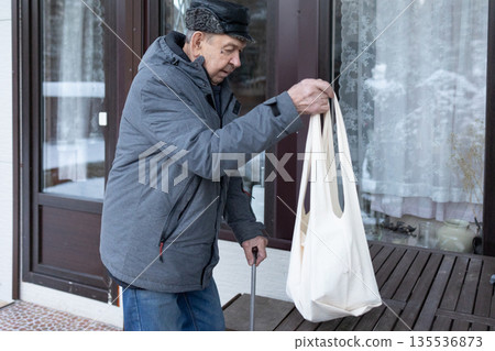 Elderly Man Walking With Cane In Snowy Courtyard Elderly Man Walking With Cane In Snowy Courtyard 135536873