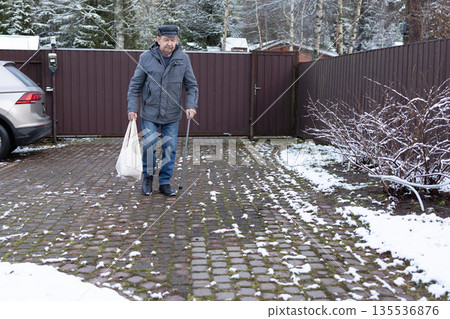 Elderly Man Walking With Cane In Snowy Courtyard Elderly Man Walking With Cane In Snowy Courtyard 135536876